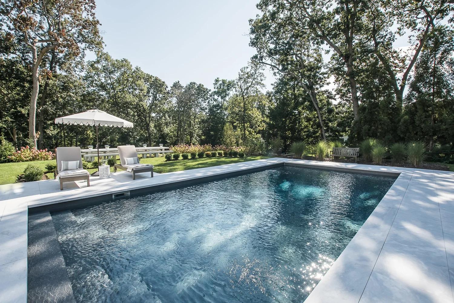 Pool terrace behind a new shingle-style house in Old Field South